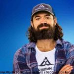 Alex Hormozi posing in a cap and plaid shirt | Alex Hormozi Net Worth