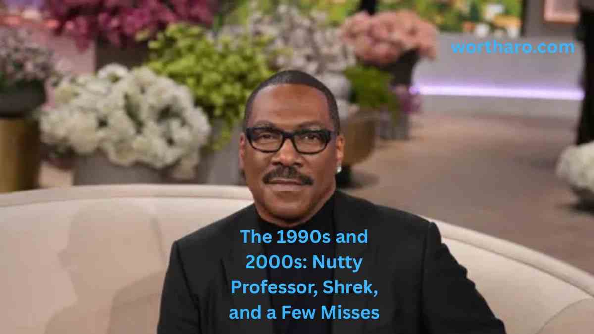 Eddie Murphy wearing a black suit and glasses while seated on a sofa, featured in an Eddie Murphy Net Worth article about his 1990s and 2000s movie career.